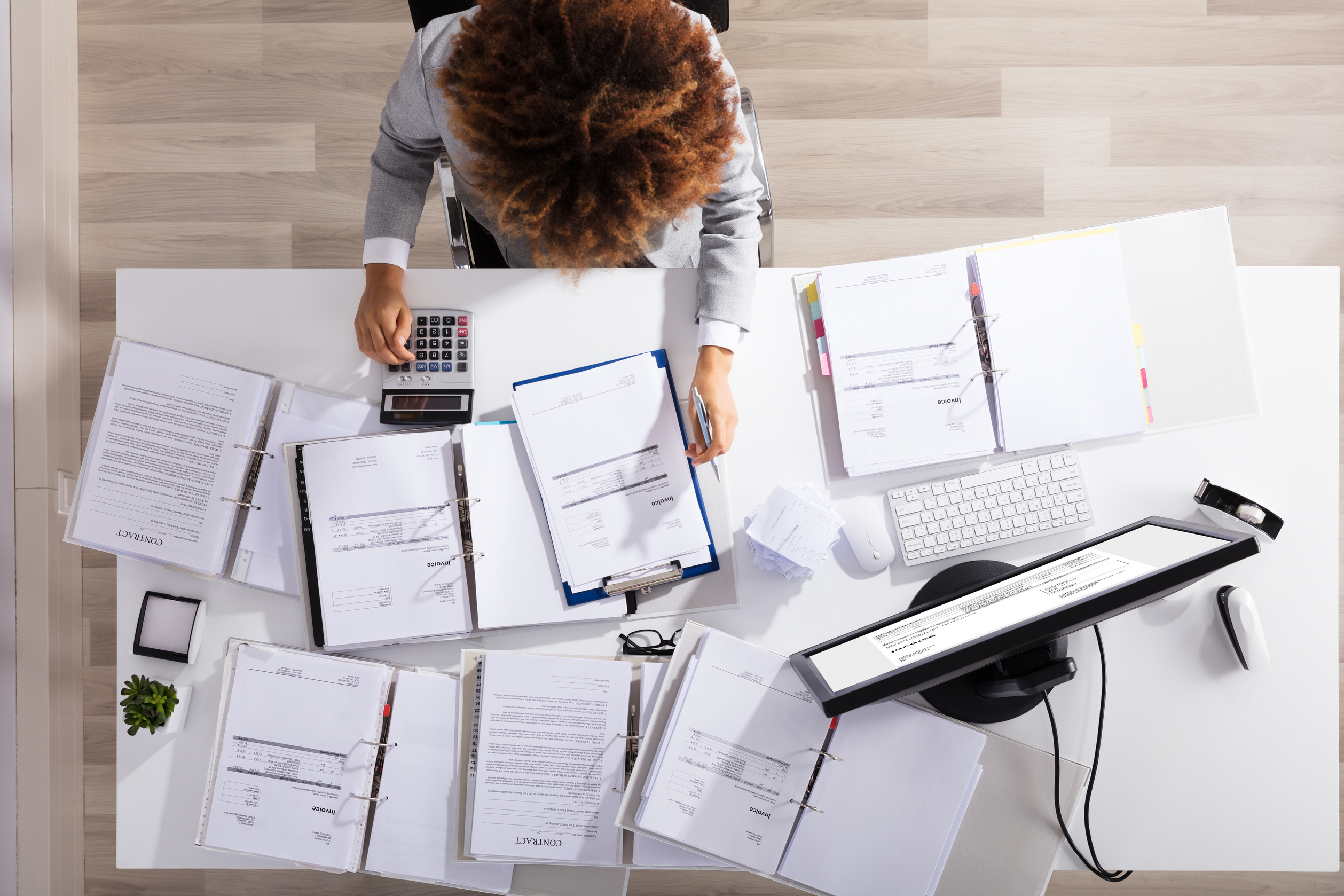 Accountant Surrounded by Documents Pressing on a Calculator